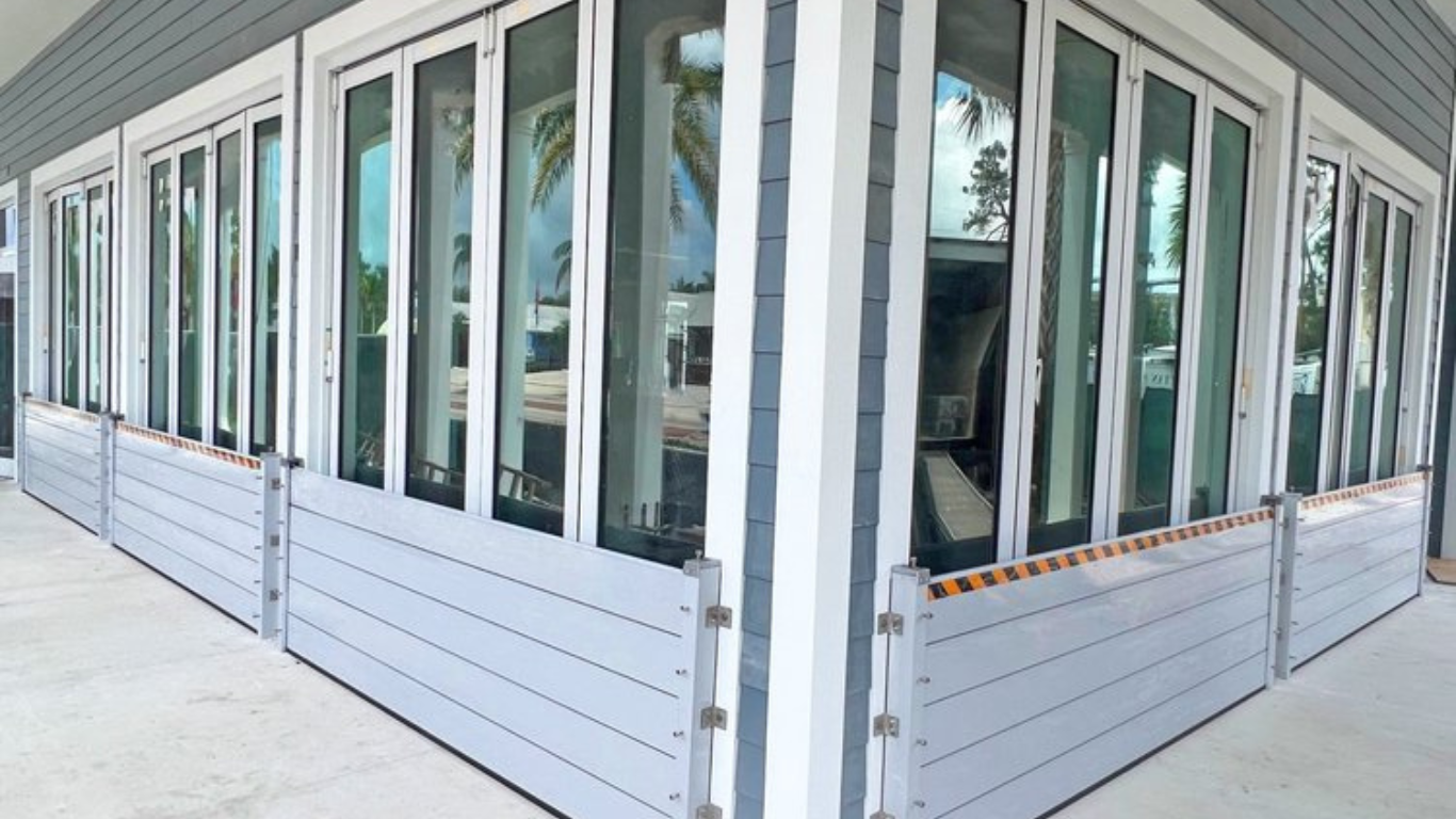 Aluminum flood plank system installed along the base of glass doors on a modern building, providing a secure and effective barrier against potential flooding.
